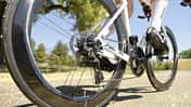 Die Aufnahme zeigt das Rennrad Look 795 Blade RS aus der Perspektive des Hinterrades während der Fahrt. Sichtbar sind der Carbonrahmen, eine Kassette mit Schaltwerk, tiefprofilige Aero-Laufräder sowie eine Scheibenbremse am Hinterrad. Der Fokus liegt auf dem Antrieb und der Bremsanlage auf einer sonnigen Straße im Freien.
